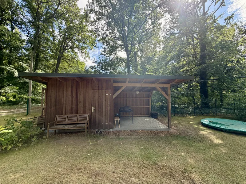Holzschuppen mit überdachtem Sitzplatz im Garten