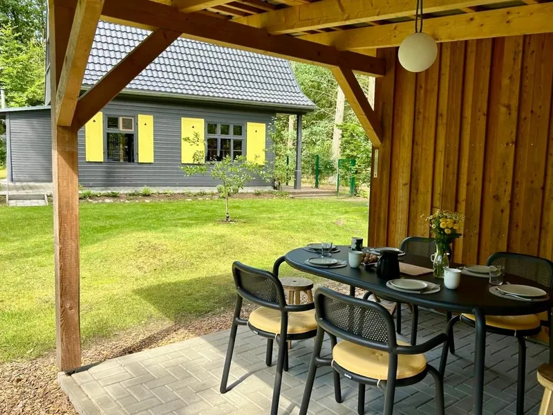 Gedeckter Tisch unter dem Schuppendach, im Hintergrund das Haus